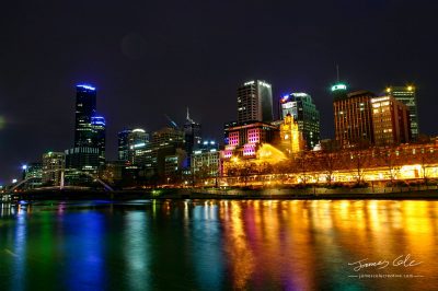 Colourful waterfront of Melbourne City and Flinders street station historic building with lights reflecting off the water