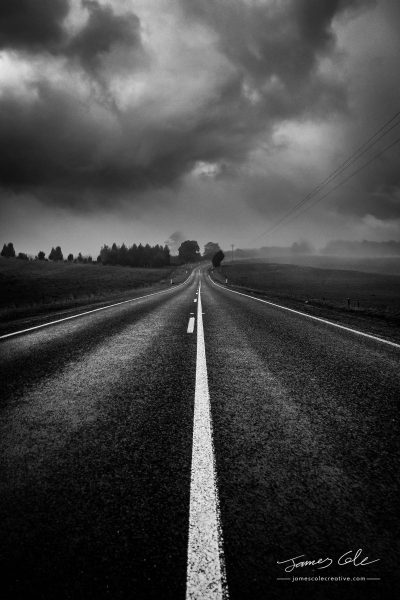 JCCI-100212 - A lonely country road shrouded in mysterious moody clouds and mist in black and white