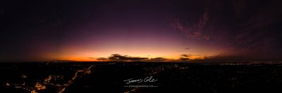JCCI-100638 - Dark horizon clouds in a deep purple sky in the afterglow of an golden sunset above the street lights aerial panoramic
