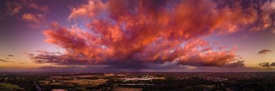 JCCI-100644 - Firey storm clouds orange pink and red at sunset with distant rain storm across the landscape aerial panoramic
