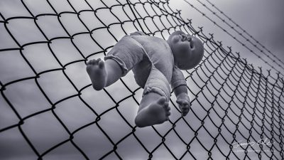 Creepy doll tied to a barbed-wire fence on a stormy day