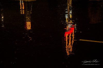 Distorted reflection of a McDonalds sign in puddles at night